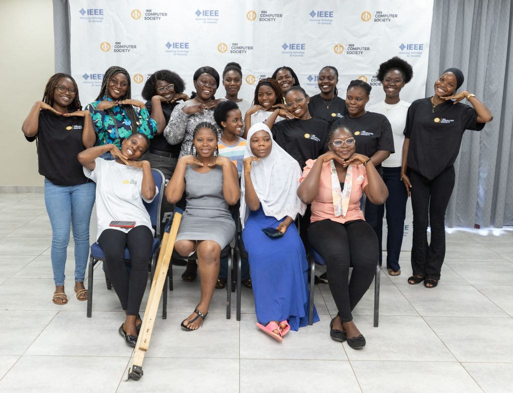 A group of smiling women posing for a photo in front of a white backdrop featuring IEEE Computer Society logos.